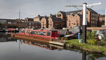 A narrowboat docked at a canal with a signpost indicating directions to the canal and Narrow Locks.