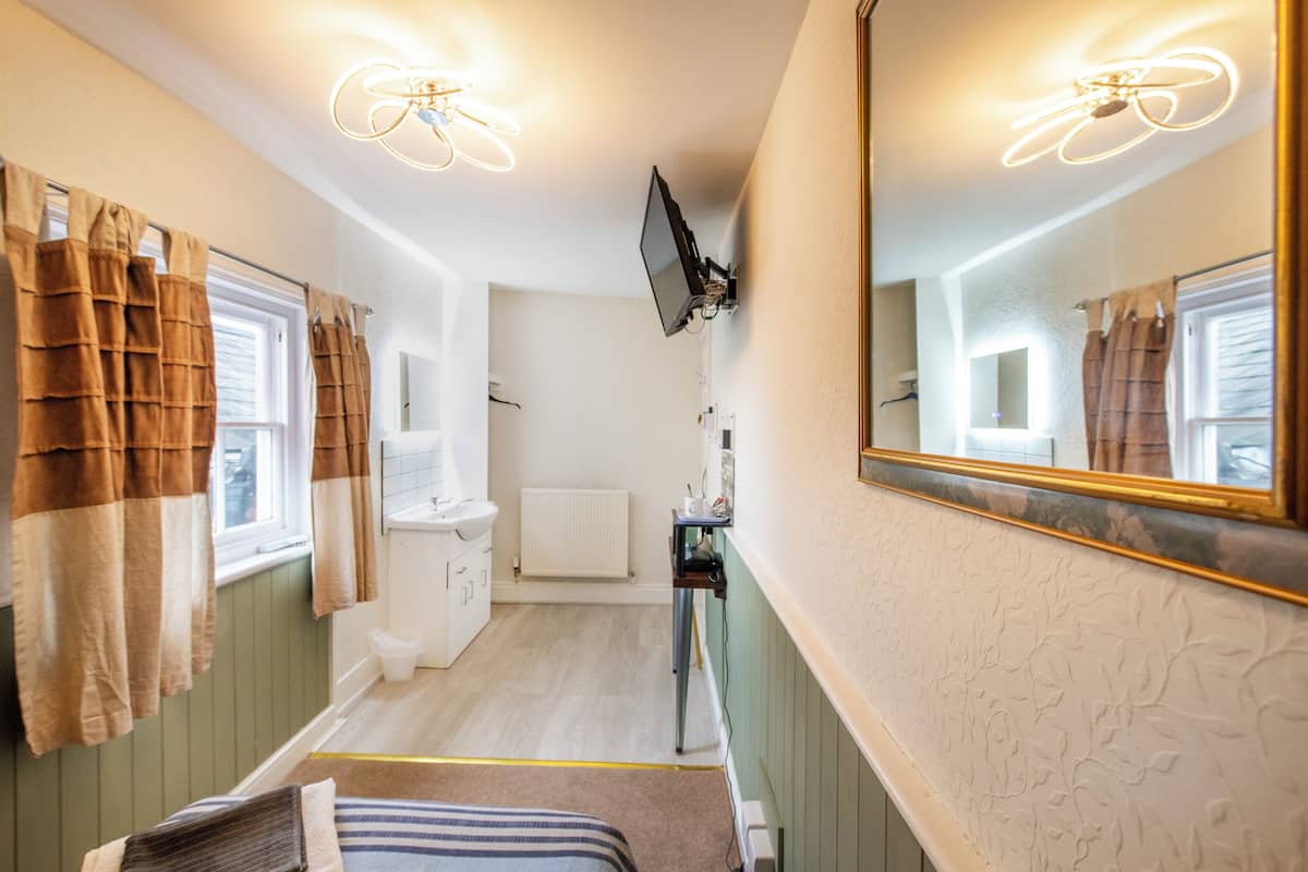 A bathroom with a large mirror, a toilet, a sink, and a shower area.