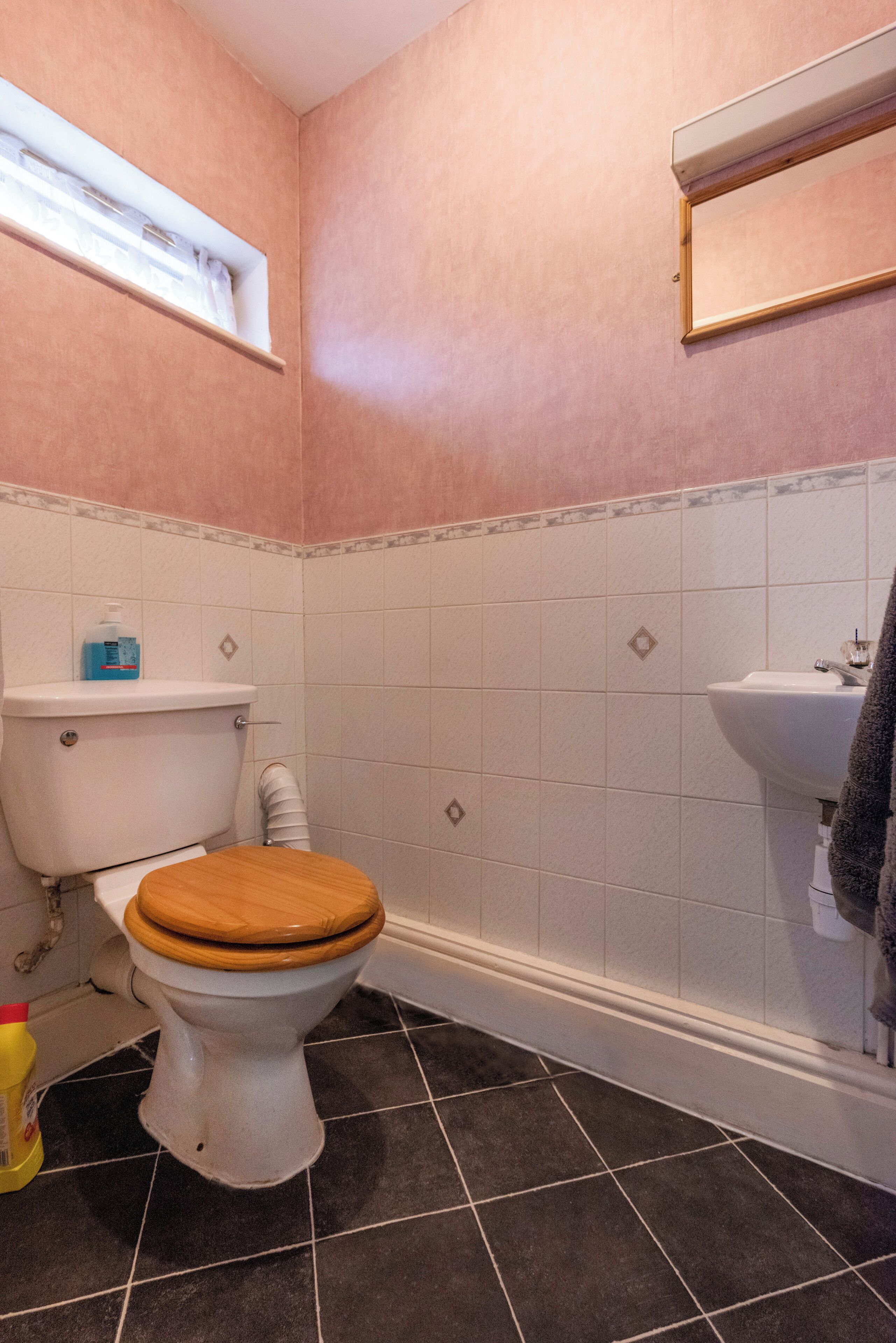 Ein Badezimmer mit Toilette, Waschbecken und Fliesenboden.