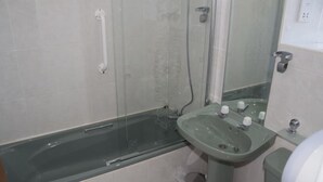 Un baño con ducha de vidrio, lavamanos y retrete.