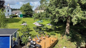 A backyard with picnic tables, lounge chairs, and a wooden deck. - The Ship Inn (Castle Douglas)