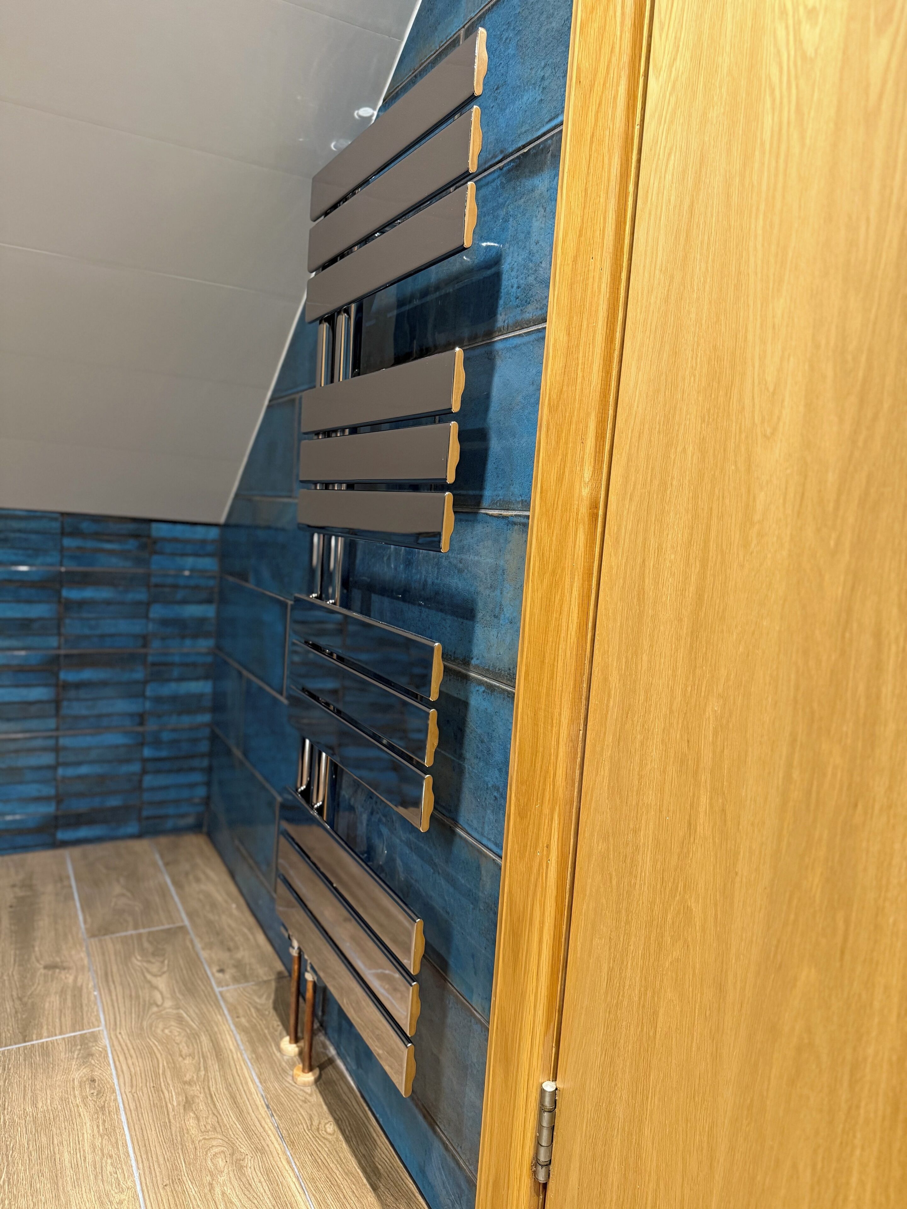 A room with a wooden door, a blue wall with horizontal panels, and a wooden floor.