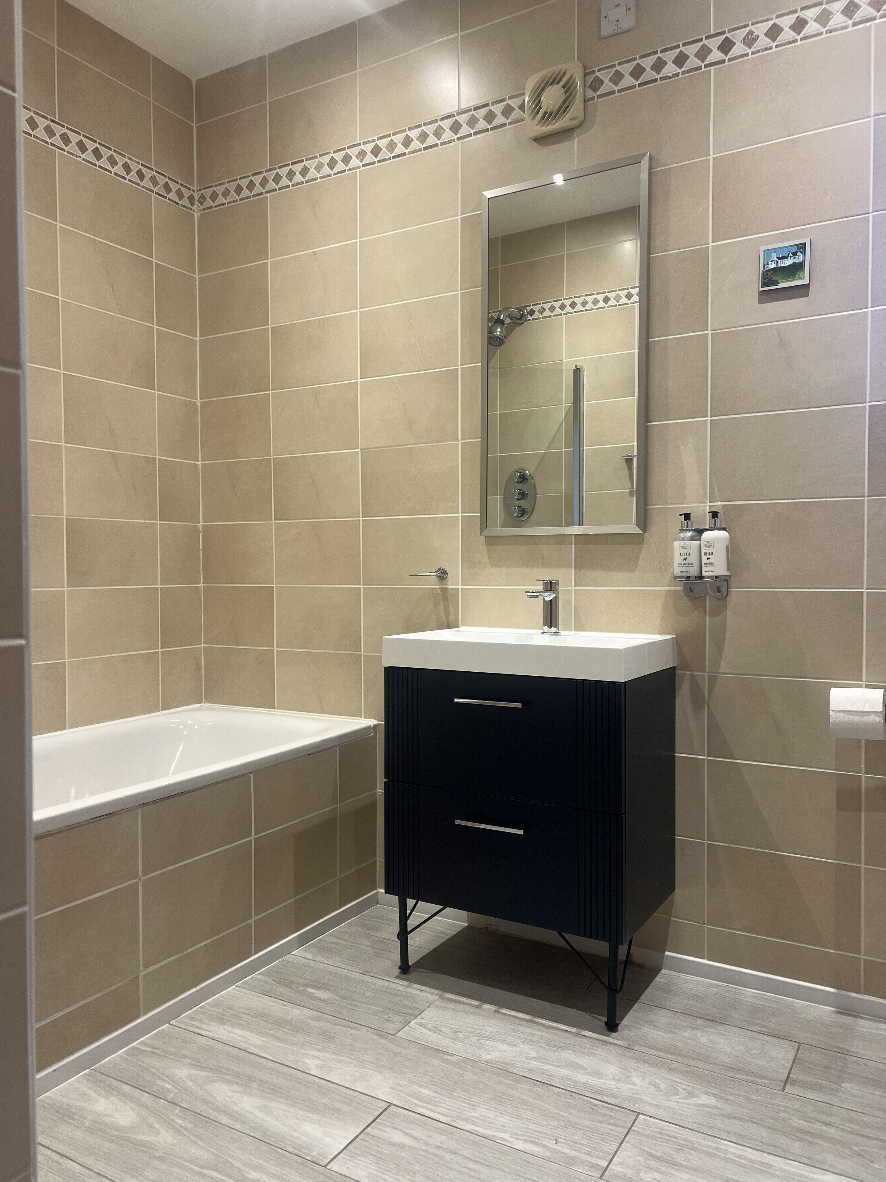 Een moderne badkamer met een badkuip, een wastafel met spiegel en een toilet.