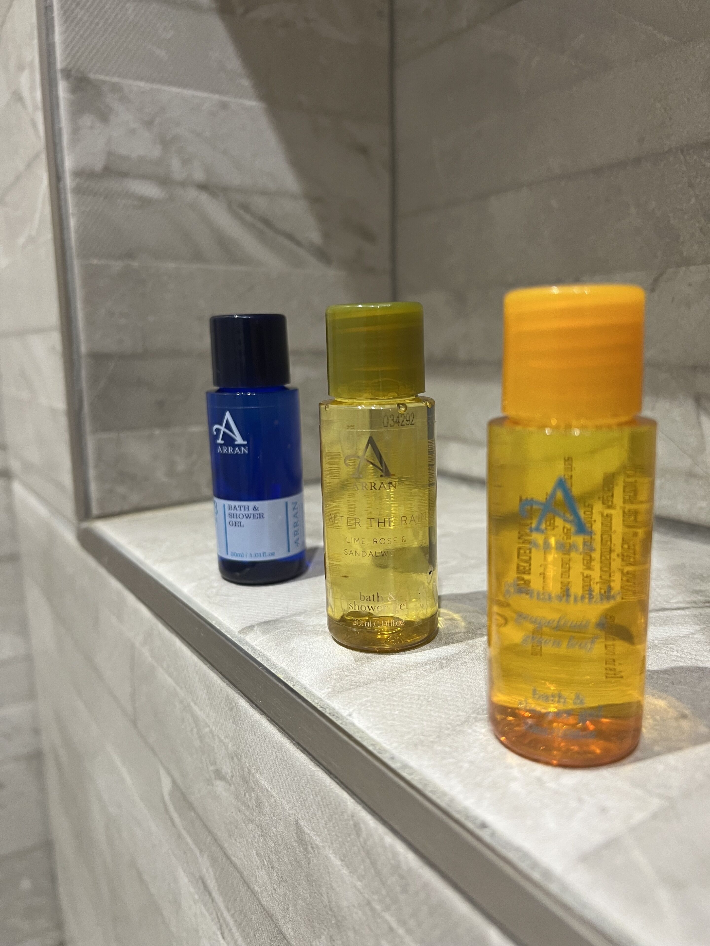 Three bottles of bath and shower gel on a shelf.
