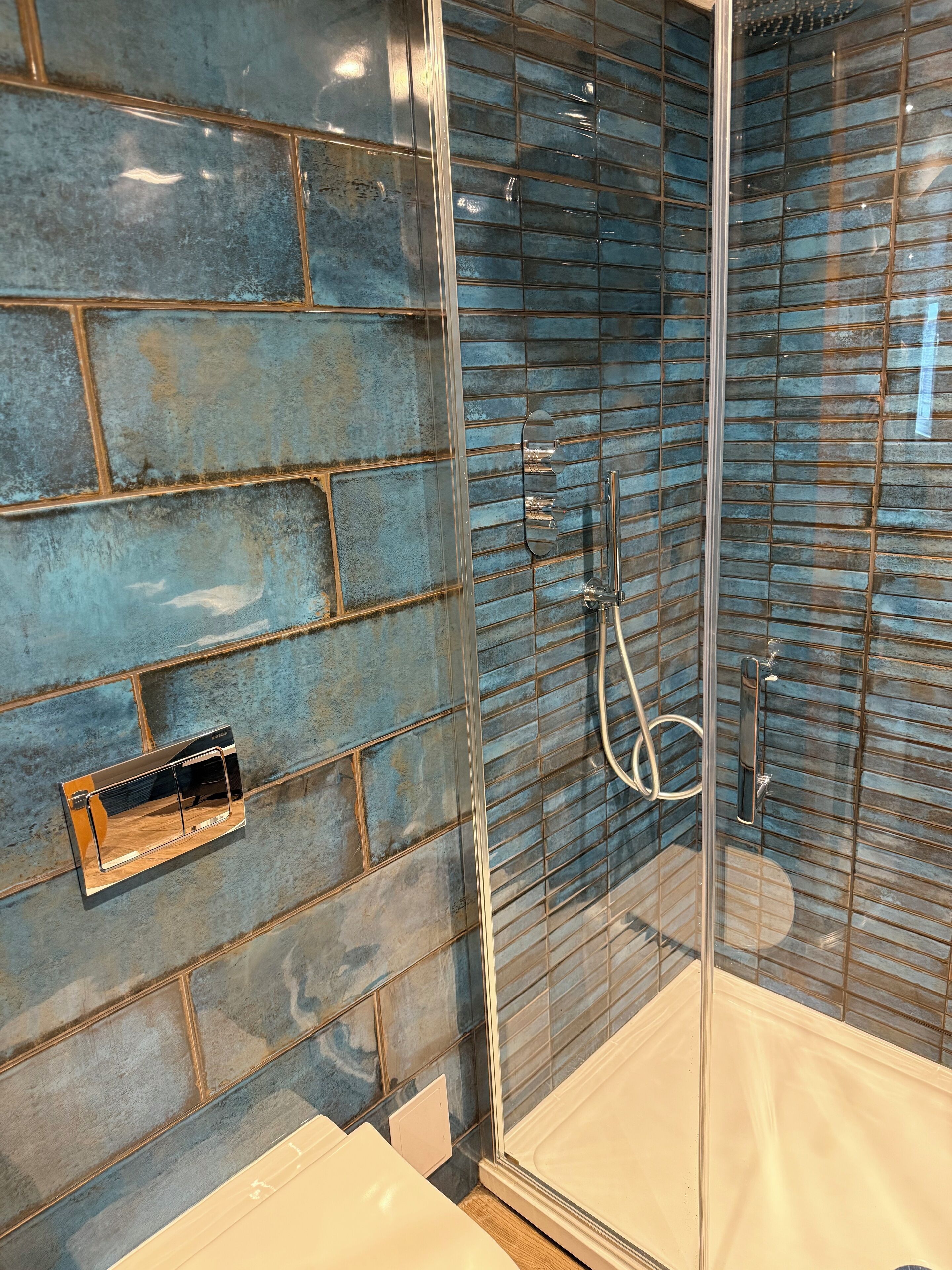 A bathroom with a glass shower enclosure, a wall-mounted towel rack, and a white sink.