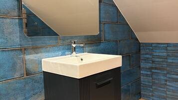 A bathroom with a white sink, dark cabinetry, and a blue-tiled wall.