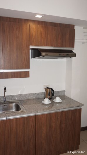 A modern kitchen with wooden cabinets, a stainless steel sink, and a kettle on the countertop. - H Hotels - Metro North Uno (Quezon City)