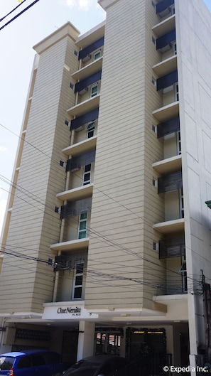 A multi-story building with a beige facade and dark blue window frames. - H Hotels - Metro North Uno (Quezon City)