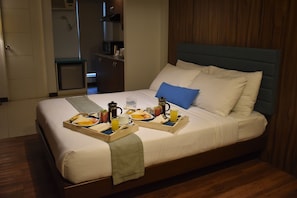 A neatly made bed with a breakfast tray, a bedside table, and a wooden headboard. - H Hotels - Metro North Uno (Quezon City)