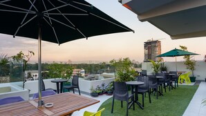 A rooftop terrace with outdoor seating, potted plants, and a view of the city skyline. - H Hotels - Metro North Uno (Quezon City)