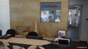 A reception area with a sign for One Nertita Hotels, a reception desk, chairs, a patterned tablecloth, snacks, and a decorative cone. - H Hotels - Metro North Uno (Quezon City)