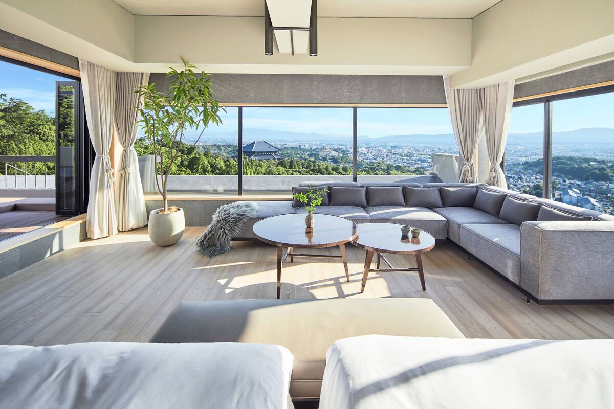 A modern living room with a large sectional sofa, two round coffee tables, and a potted plant.