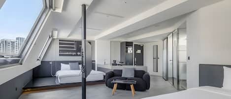 Ett modernt hotellrum med en stor säng, en soffa, ett skrivbord och en balkong med utsikt över staden.