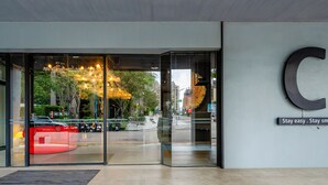 A hotel entrance with a large glass door, a 'C' sign, and a 'Stay easy. Stay safe.' sign. - CHECK inn Taichung Liming (Taichung)