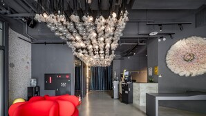 A modern lobby with a red seating area, a water dispenser, a reception desk, and a unique chandelier. - CHECK inn Taichung Liming (Taichung)
