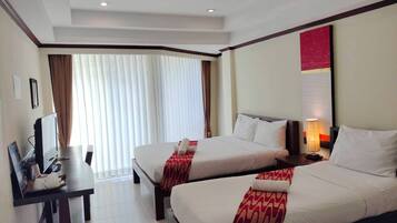 Habitación de hotel con dos camas, un escritorio con computadora y televisión.