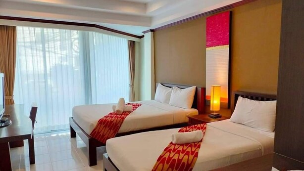 A hotel room with two beds, a desk, and a large window with curtains. - Khon Kaen Orchid Hotel (Khon Kaen)