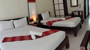 Habitación de hotel con dos camas, una mesita de noche con lámpara, un espejo y una pared de acento roja.