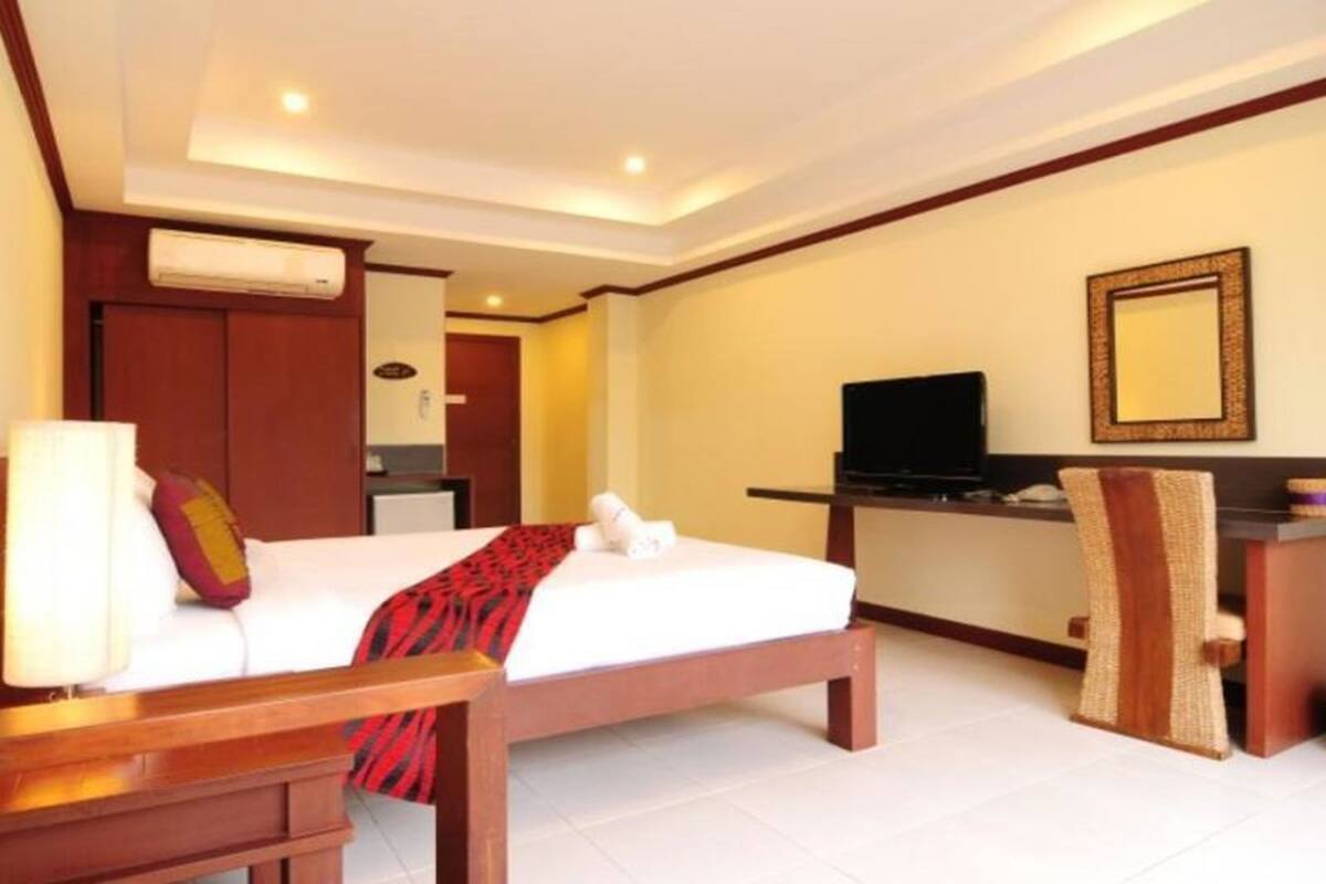 A hotel room with a bed, a desk, a television, and a mirror.