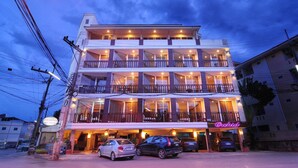 A multi-story hotel with balconies, a parking area, and a neon sign. - Khon Kaen Orchid Hotel (Khon Kaen)