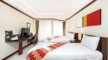 A hotel room with two beds, a desk with a computer, a television, and a breakfast setup.