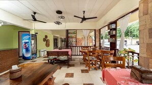 A cozy indoor seating area with wooden furniture, ceiling fans, and a vending machine. - Khon Kaen Orchid Hotel (Khon Kaen)