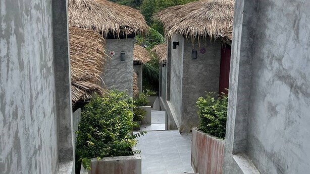 Un couloir donnant sur des bâtiments traditionnels aux toits de chaume, avec un escalier menant à un niveau supérieur.