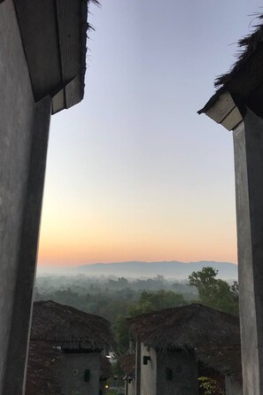 Une vue d’un paysage rural avec des bâtiments aux toits de chaume et un horizon brumeux.