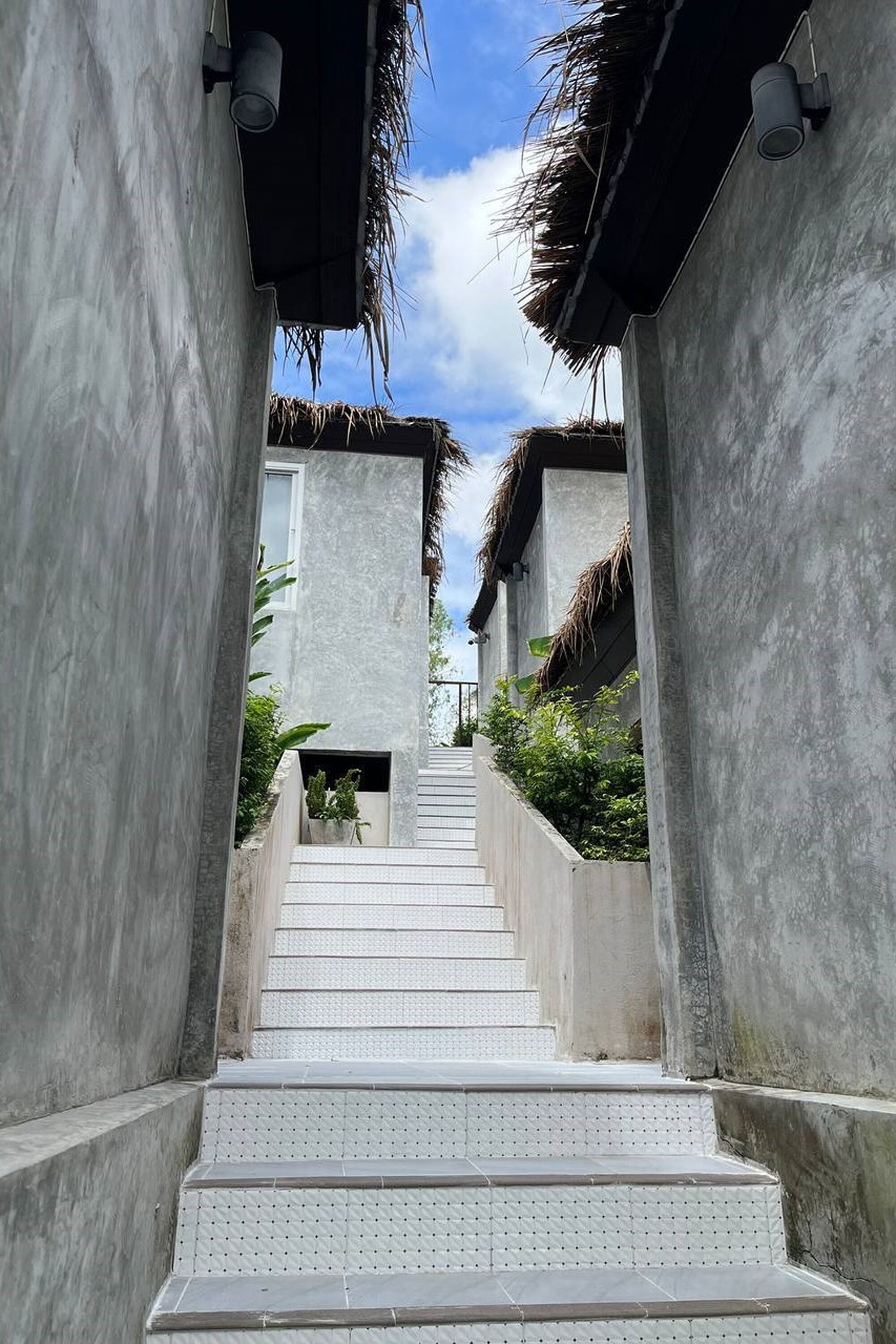 A concrete staircase leading to a building with thatched roofs.