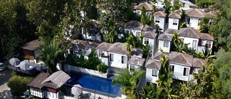A residential area with multiple houses, a swimming pool, and lush greenery.