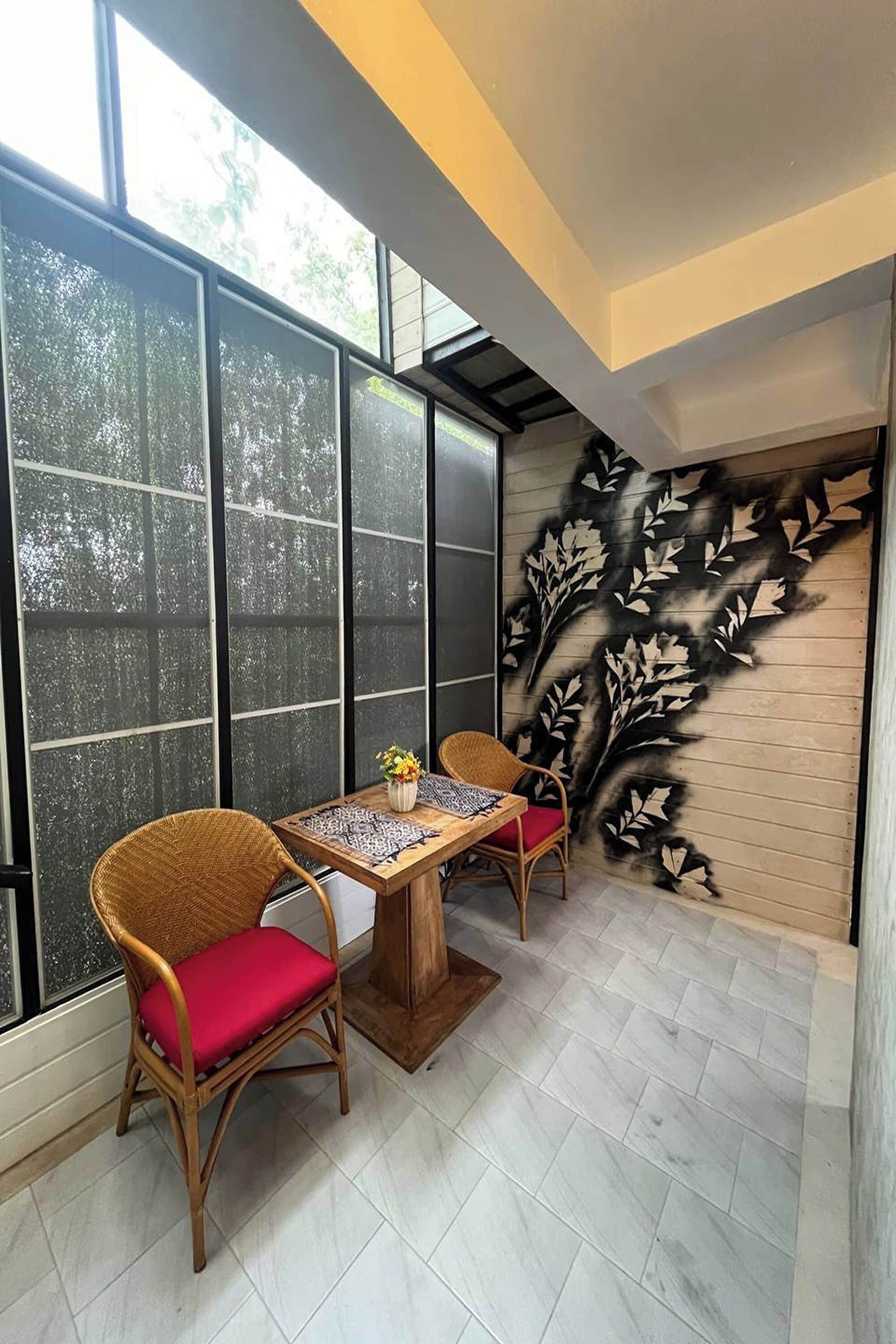 A corner room with a large window, a wall mural, and a dining table with chairs.