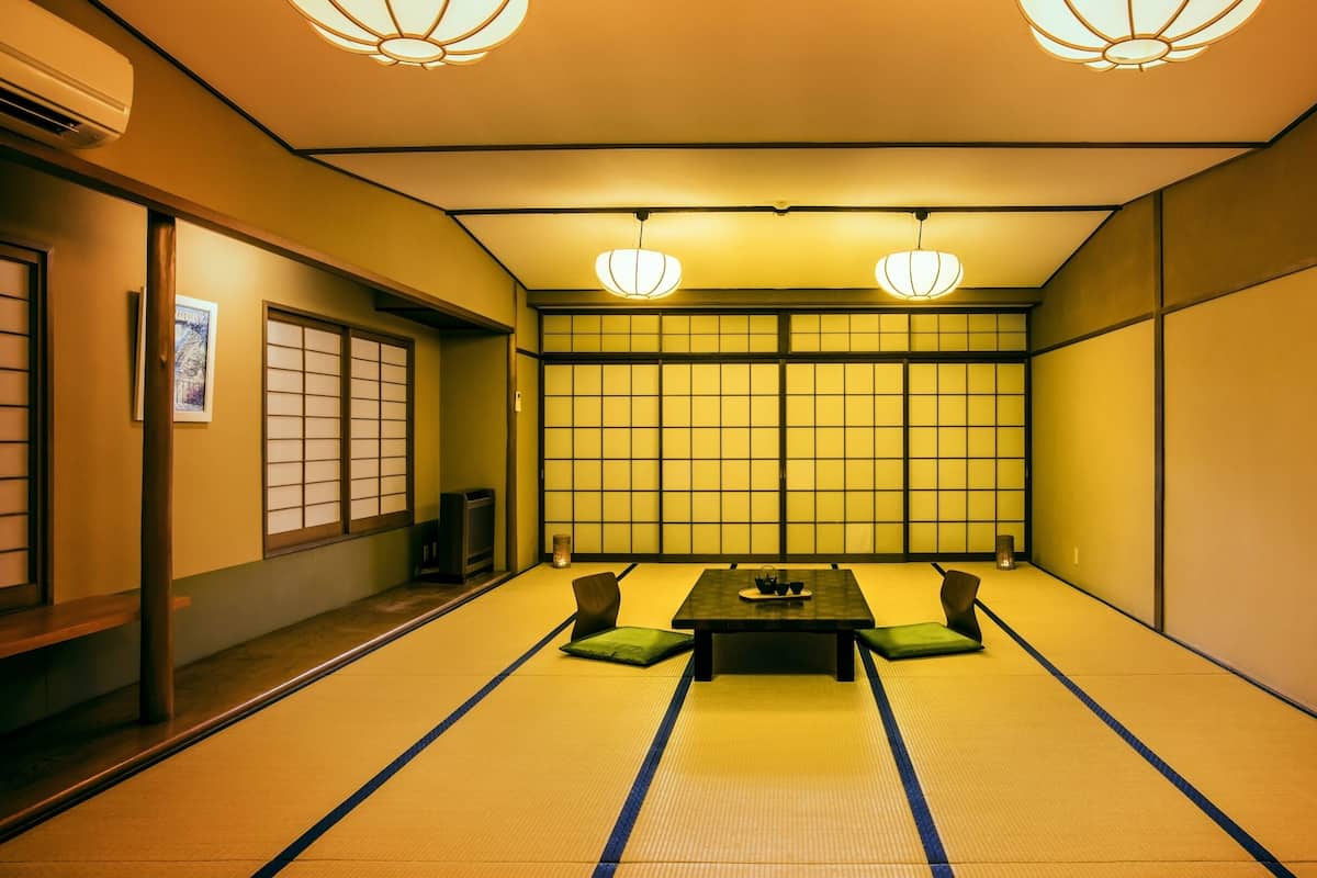 A traditional Japanese room with tatami flooring, a low table with cushions, and shoji screens.