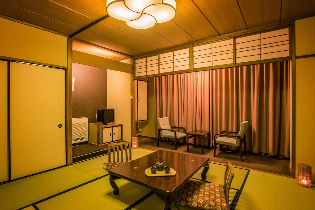A traditional Japanese-style room with tatami flooring, a low table with a tea set, and sliding doors.