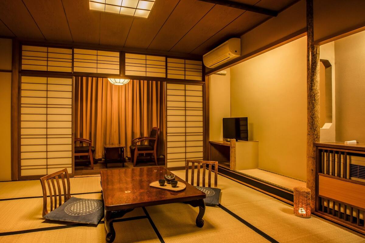 A traditional Japanese room with tatami flooring, a low table, and sliding doors.