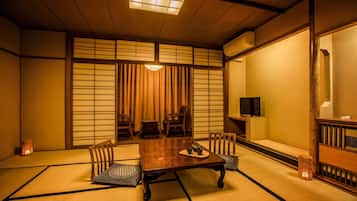 Una habitación japonesa tradicional con suelo de tatami, una mesa baja y puertas correderas.