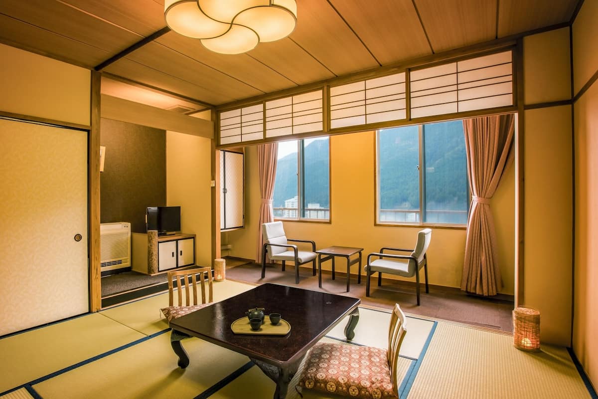 A traditional Japanese room with tatami flooring, a low table with a tea set, and sliding doors.