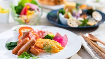 A plate with various foods including sausages, a slice of salmon, and vegetables.