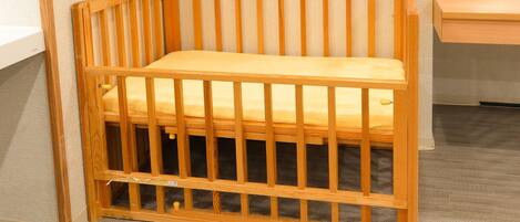 A wooden crib with a mattress, a wooden side table, and a carpeted floor.