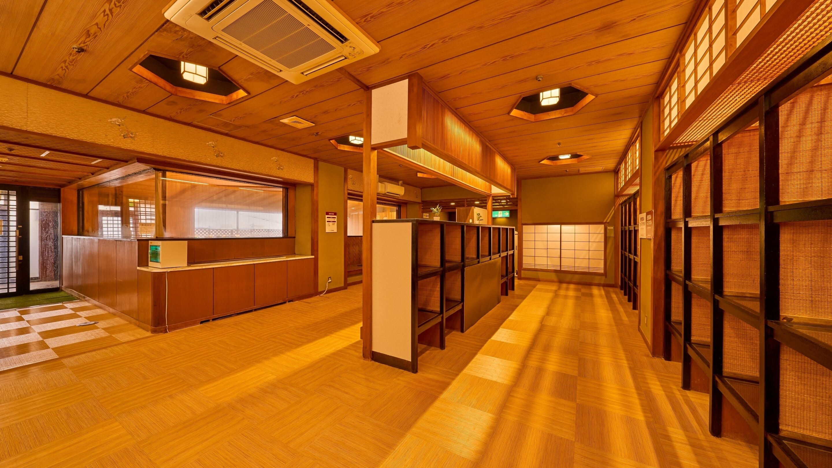 A hallway with wooden floors, a reception desk, and traditional Japanese sliding doors.