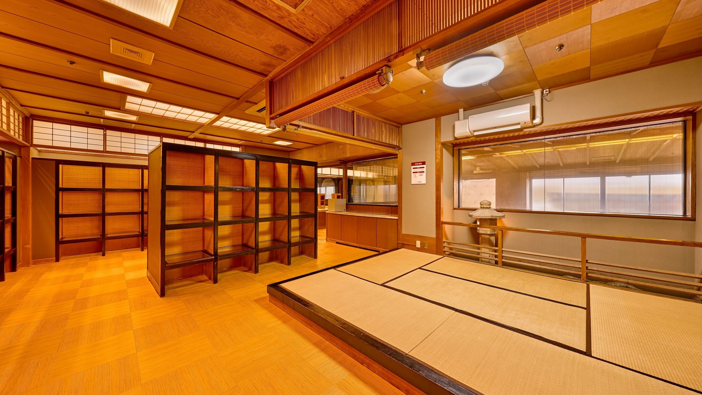 Een traditionele Japanse kamer met tatami vloeren, houten schuifdeuren en een uitzicht door een groot raam.