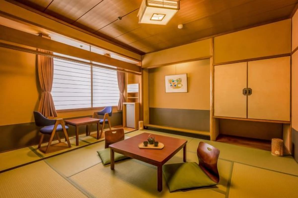 A traditional Japanese room with tatami flooring, a low table with cushions, and sliding doors.