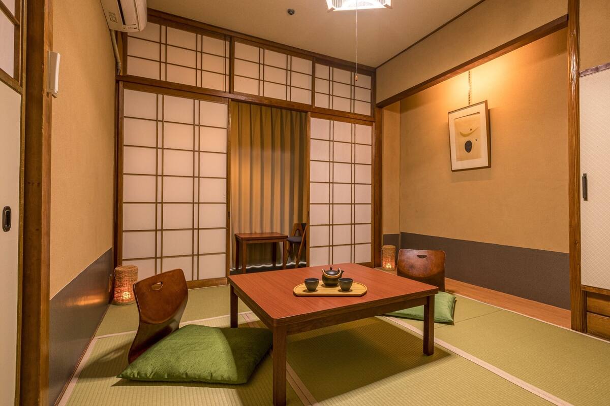 A traditional Japanese room with tatami flooring, a low table with a tea set, and shoji screens.