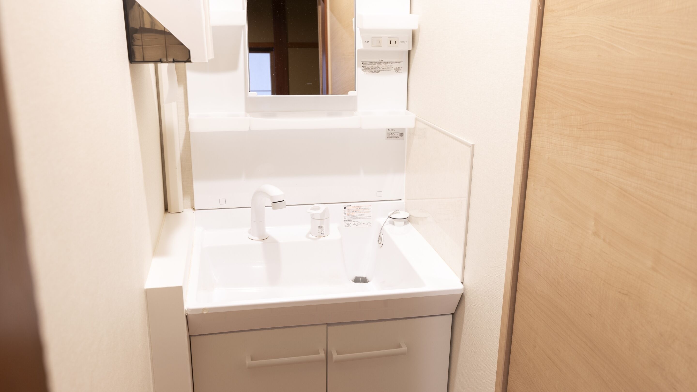 A bathroom with a white sink, mirror, and cabinet.