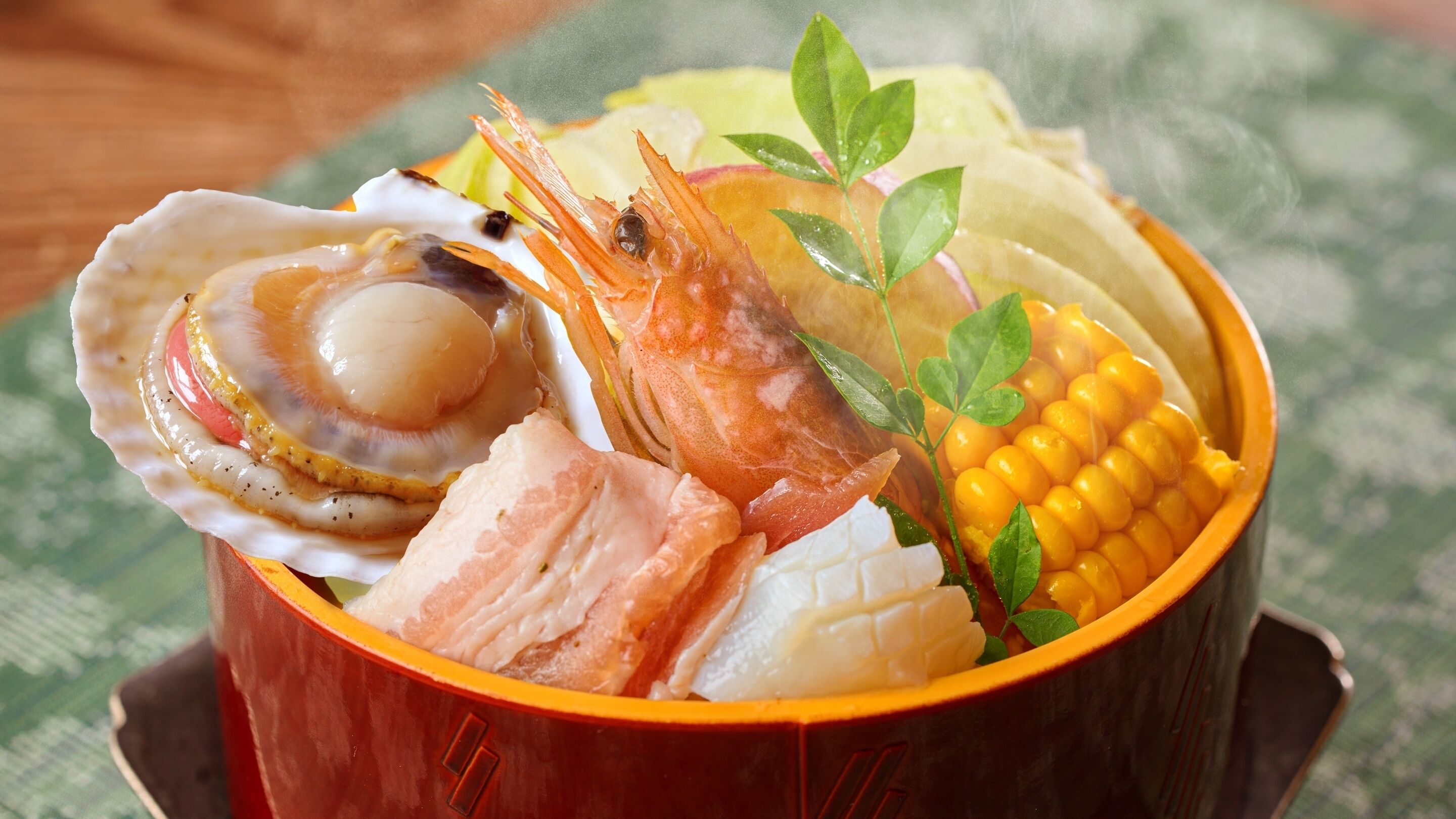 A bowl of seafood including shrimp, scallop, salmon, corn, and a leafy garnish.