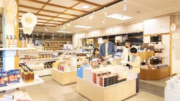 A well-lit store with wooden beams, shelves stocked with various products, and a counter where customers are interacting with staff.