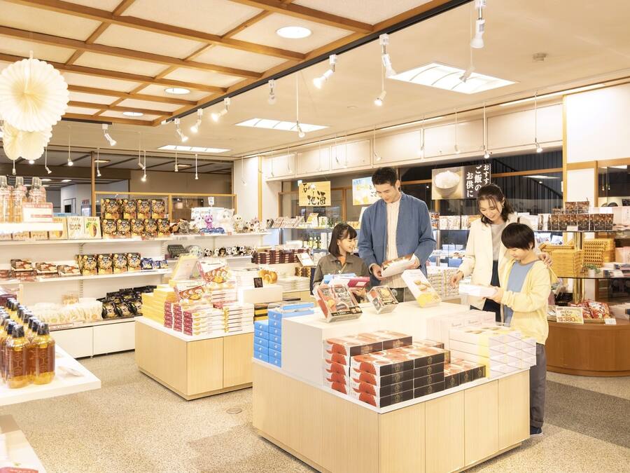 A well-lit store with wooden beams, shelves stocked with various products, and a counter where customers are interacting with staff.