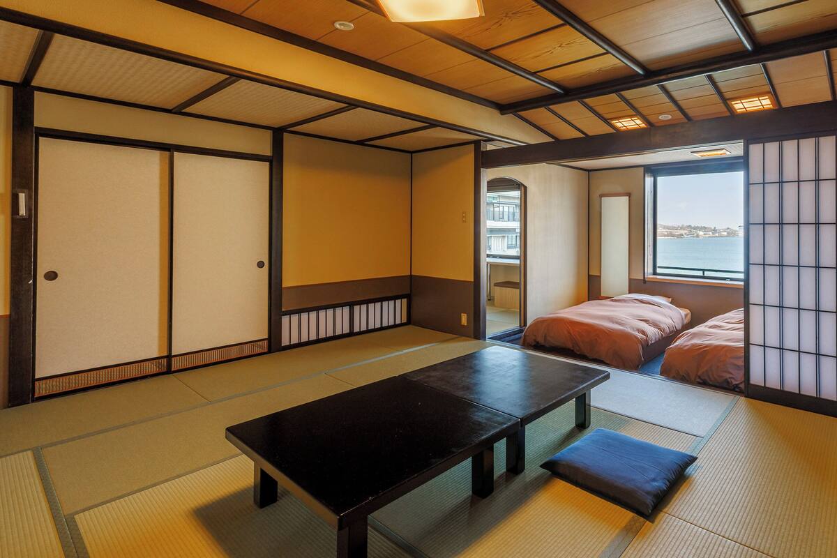 Una habitación japonesa tradicional con suelo de tatami, una mesa baja y puertas correderas.