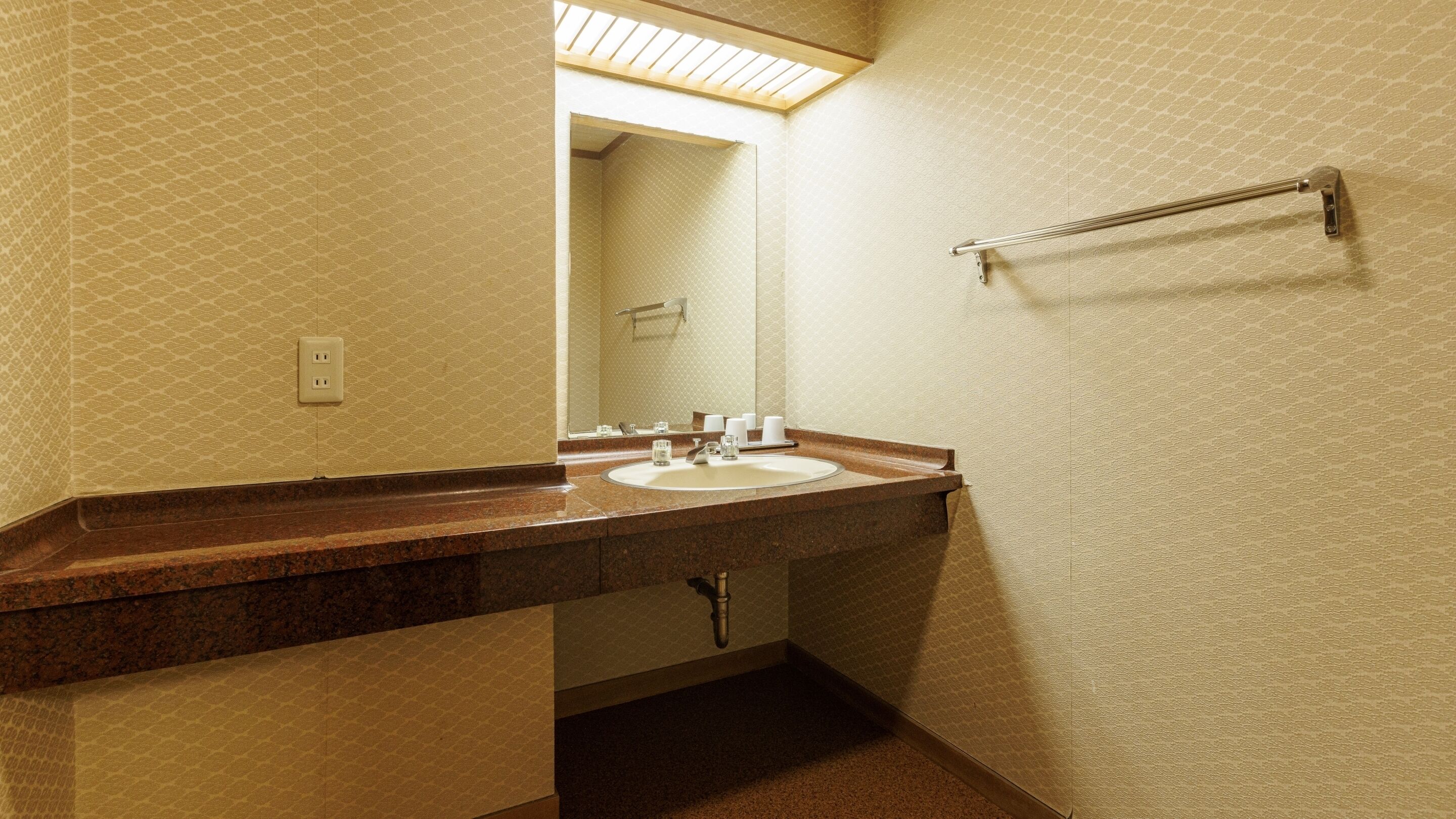 Un baño con lavabo, espejo, perchero y paredes con diseño.