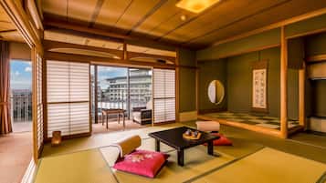Una habitación japonesa tradicional con suelo de tatami, una mesa baja con un juego de té y un puertas correderas que dan a un balcón.