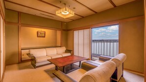 A traditional Japanese room with tatami flooring, a low wooden table, a sofa, and a sliding shoji screen. - Ooedo Onsen Monogatari Premium Kaga Maruya (Kaga)